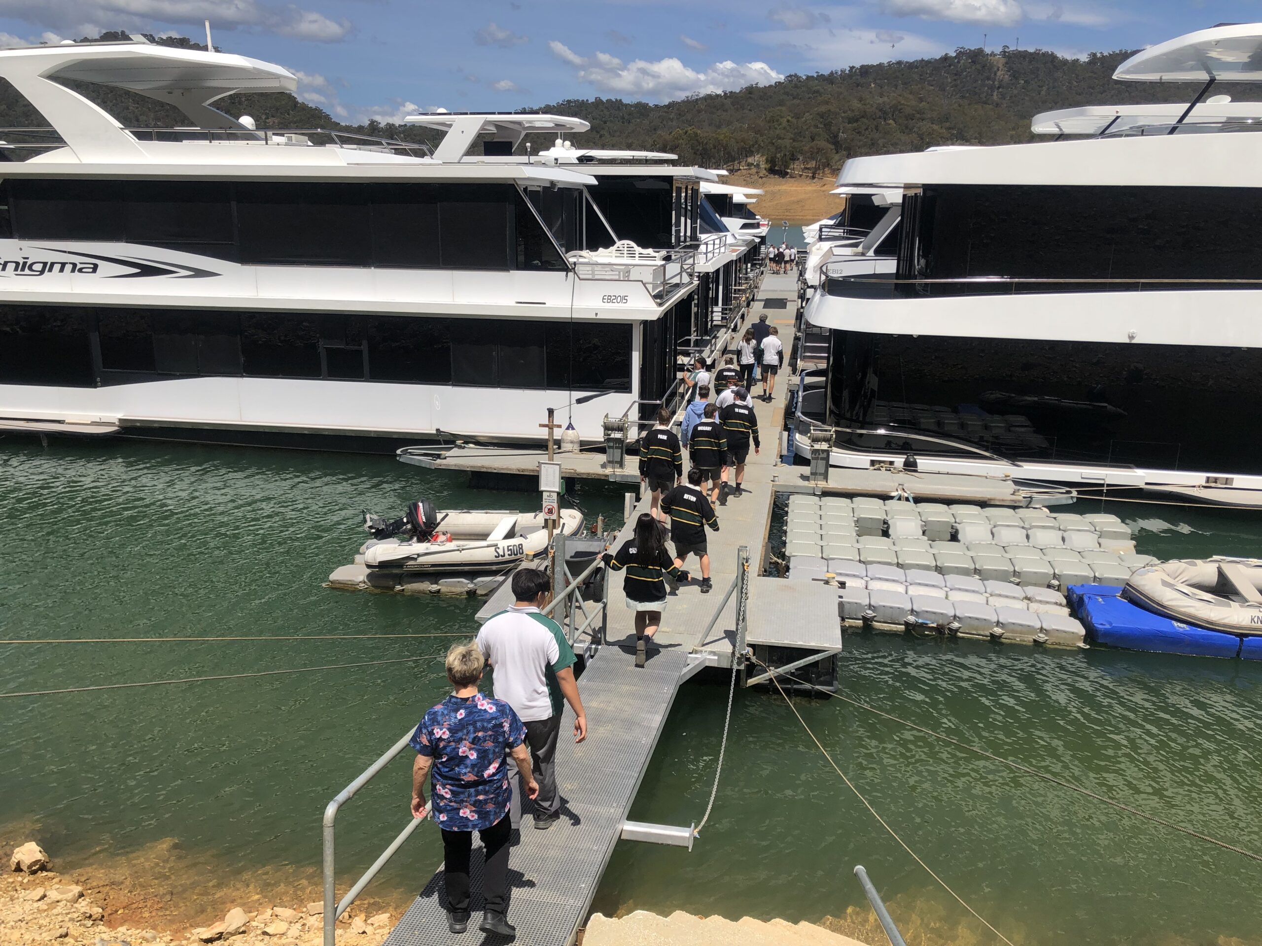 Students walking the pontoon between houseboats during a Boating Careers Immersion Day